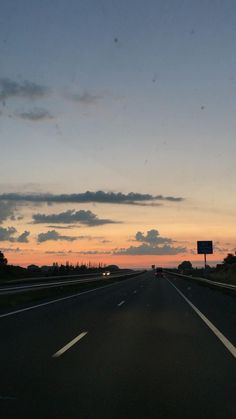 the sun is setting on an empty highway