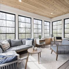 a living room filled with furniture and lots of windows on top of a wooden floor