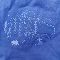 a blue t - shirt with an image of a bear and cabin in the woods