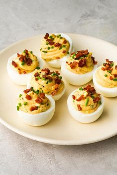 deviled eggs with bacon and chives on a white plate