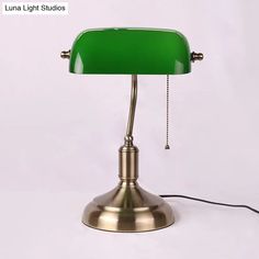 a green lamp sitting on top of a white table next to a black corded phone