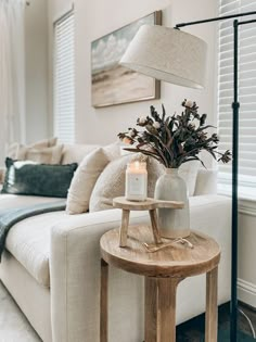 a living room filled with furniture and a lamp on top of a wooden table next to a white couch