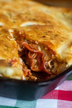 a casserole with meat and cheese in a pan on a checkered table cloth