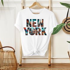 the new york t - shirt is hanging on a clothes rack next to a potted plant