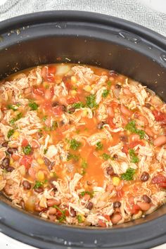 a crock pot filled with beans, meat and veggies