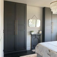 a bedroom with gray painted cabinets and a chandelier hanging from the ceiling over a bed