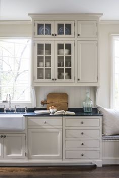 a kitchen with white cabinets and black counter tops in front of a window that is open to the outside