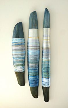 three pieces of art made out of wood and painted with blue, white and green stripes