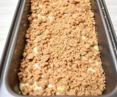 a pan filled with food sitting on top of a wooden table covered in crumbs