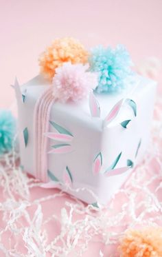 a white gift box with pom - poms on it