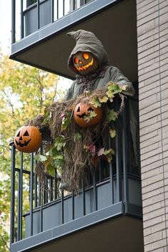 a scarecrow with two jack o lanterns on his balcony