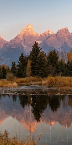 the mountains are reflected in the still water of this lake as the sun is setting