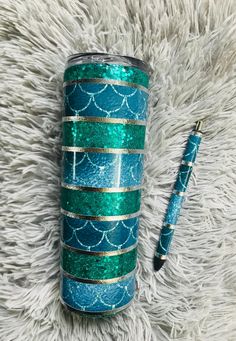 a blue and green glitter tumbler next to a pen on top of a white rug