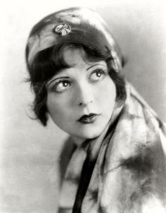 an old black and white photo of a woman wearing a hat with flowers on it