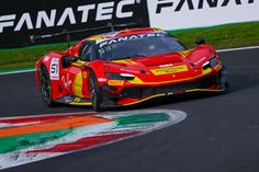 a red and yellow sports car driving on a race track in front of a fanatec sign