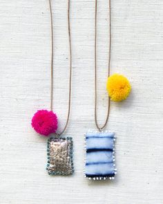 two necklaces with pom - poms hanging from them on a white surface