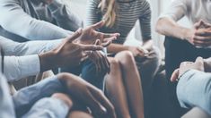 group of people sitting in a circle with their hands together