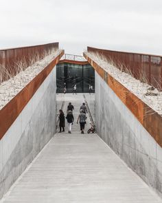 two people walking up the stairs to an open area with concrete walls and metal railings