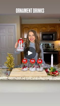 a woman standing in front of a kitchen counter with candles and ornaments on top of it