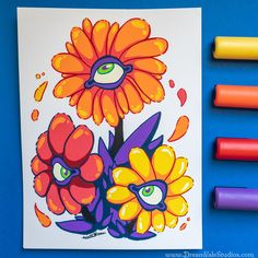 an art project with markers and crayons on a blue background, depicting flowers