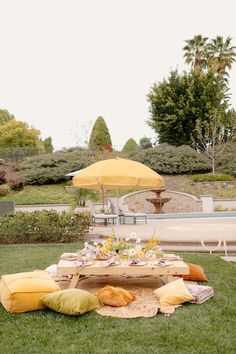 an outdoor picnic setting with yellow umbrellas and pillows