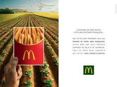 a person holding up a mcdonald's advertisement in front of a field full of carrots