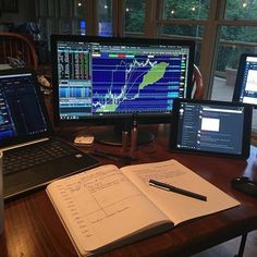 three computer monitors sitting on top of a wooden desk next to a laptop and monitor