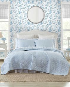 a bedroom with blue wallpaper and white bedding