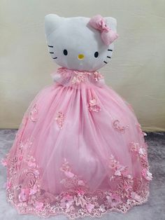 a stuffed hello kitty doll in a pink dress with flowers on it's skirt