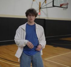 a young man standing in front of a basketball hoop with his hands on his hips