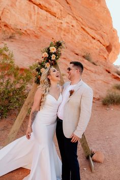 a bride and groom standing in front of a rock formation