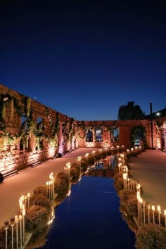 an outdoor area with many candles lit up in the middle and water running through it