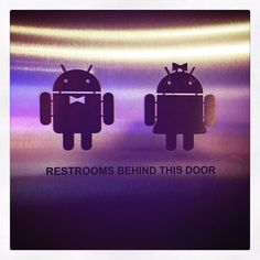 an image of two androids with the caption restrooms behind this door written on them