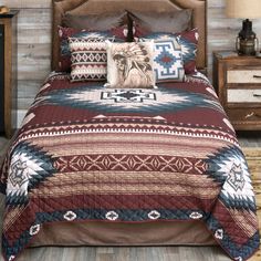 a bed covered in a brown and blue comforter next to a night stand with two nightstands