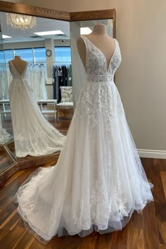 a wedding dress on display in front of a mirror