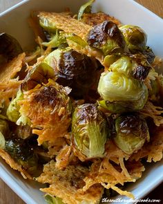 brussel sprouts in a white bowl with crispy bread on the side