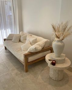 a white couch sitting next to a table with a vase on it