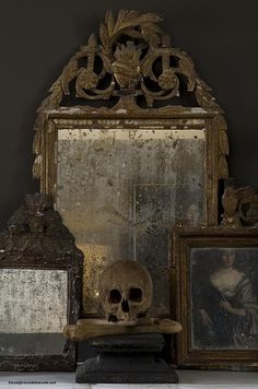 there is a skull sitting on a table next to two framed pictures and a mirror