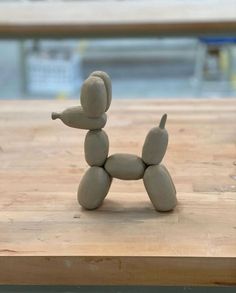 a toy dog made out of clay sitting on top of a wooden table next to a pool