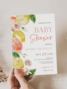 a person holding up a baby shower card with lemons and oranges on it