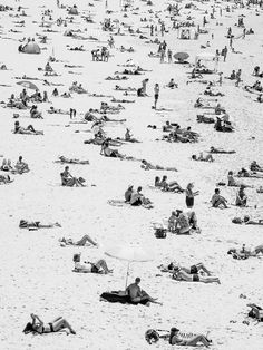 many people are laying and standing on the beach