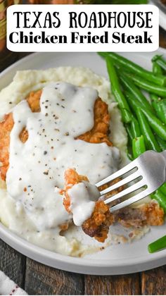 a white plate topped with mashed potatoes covered in gravy and green beans