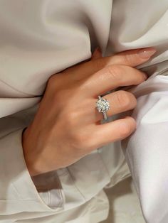 a woman's hand with a diamond ring on top of her finger and white satin