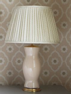 a white lamp sitting on top of a table next to a wallpapered wall