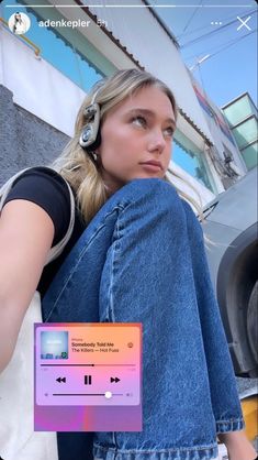 a woman sitting on the ground with headphones in her ears and an mp3 player next to her