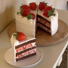 two slices of cake with white frosting and strawberries on the top one slice has been cut