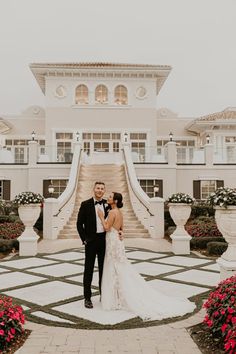 a bride and groom standing in front of a mansion