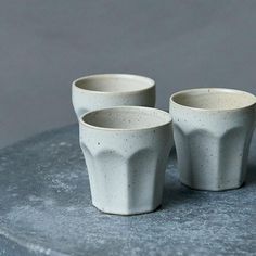 three white cups sitting on top of a stone slab