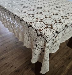 a table with a white doily on it sitting on a wooden floor next to a wall