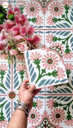 a person holding a flower in front of a tiled wall